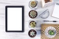 Top view on a wooden desk with a tablet, cacti, a notebook, spiral notebook with golden dots