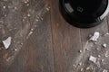 Top view on wooden floor being cleaned by a black robotic vacuum