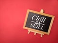 Top view of wooden frame with the word Chill is a skill on red background