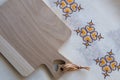 Top view of a wooden kitchen board. The board is on an old embroidered fabric. The board is clean and there is nothing on it