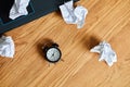 Top view of wooden office desk with clock,, notebook, crumpled paper balls Royalty Free Stock Photo