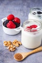 Top view of wooden spoon with brown sugar, walnuts, bowl with raspberries, blackberries and two jars of yogurt with raspberries, o Royalty Free Stock Photo