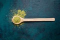 Top view of wooden spoon filled with green matcha tea powder with a little bit powder spilled out on emerald backdrop. Royalty Free Stock Photo