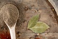 Top view of a wooden spoon full of black pepper and bay leaf on wooden barrel background, selective focus. Royalty Free Stock Photo