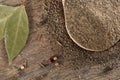 Top view of a wooden spoon full of black pepper and bay leaf on wooden barrel background, selective focus. Royalty Free Stock Photo