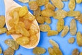 Top view of a wooden spoon with yellow dried raisins on blue background Royalty Free Stock Photo