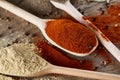 Top view of a wooden spoons full of paprica and black pepper on wooden barrel background, selective focus. Royalty Free Stock Photo