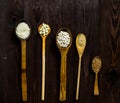 Top view of wooden spoons on which lie an assortment of different cereals on a wooden table. Royalty Free Stock Photo