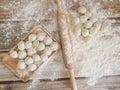 Top view on wooden table with homemade food. hand made raw dumplings on wooden dish and rolling pin covered with flour.