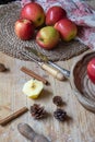 Top view of wooden table with red apples, kitchen utensils, cinnamon, flour and tablecloth