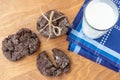 Top view on wooden table served with dark blue dinner napkin and glass of fresh milk with a group of baked choco sweet biscuits