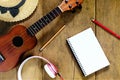 Top view wooden table, There are notebooks, pencils, hats, earphones, and ukulele on the wood table, relaxation shots.