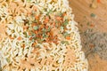 Top view of a wooden tray with chopsticks next to a bowl of instant noodles topped with spices