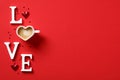 Top view word `LOVE` made out of letters and heart-shaped coffee cup on red background. Valentine`s Day concept