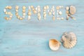 Top view word summer of sea shell on light blue wooden textured for holiday time background Royalty Free Stock Photo