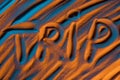 Top view of word trip written in sand with smooth waves and color filter.