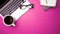 Top view of work place desk, laptop with notebook,glasses  and cup of black coffee on empty bright pink background Royalty Free Stock Photo