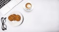 Top view of work place table, laptop with glasses cookies and cup of cappuccino on white background Royalty Free Stock Photo