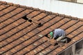 Top view of a worker removing tiles from a house to renovate the roof