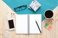 Top view of working desk with blank notebook with pencil, coffee cup, colorful note pad, eyeglasses and mobile phone on wooden bac Royalty Free Stock Photo