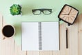 Top view of working desk with blank notebook with pencil, coffee cup, eyeglasses, retro alarm clock and plant on wooden background Royalty Free Stock Photo