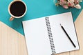 Top view of working desk with blank notebook with pencil, coffee cup and flowers on wooden background Royalty Free Stock Photo