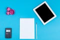 Top view of the workspace on blue background. calculator, a notebook, a pencil, a tablet computer and pink flower buds Royalty Free Stock Photo