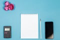 Top view of the workspace on a blue background. calculator, Notepad, pencil, smartphone and pink flower buds Royalty Free Stock Photo
