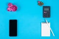 Top view of the workspace on a blue background. calculator, Notepad, pencil, smartphone and pink flower buds Royalty Free Stock Photo