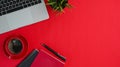 Top view of workspace with, laptop, house plant, notebook, coffee cup and copy space on red background. Royalty Free Stock Photo