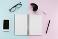 Top view of workspace desk with blank notebook, eye glasses, smart phone, ribbon and office stationery on color background Royalty Free Stock Photo