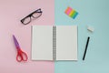 Top view of workspace desk with blank notebook, glasses and office stationery set on pink and blue background Royalty Free Stock Photo