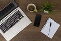 Top view of workspace. Table desk with laptop, cell phone, coffee, notepad, pen and plant with empty space background for design.