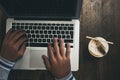 Top view of workstation with modern technology laptop computer and hands to use it and write - coffee or cappuccino drink at its Royalty Free Stock Photo