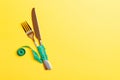 Top view of wrapped fork and knife in tape measure on yellow background. Healthy eating and diet concept Royalty Free Stock Photo