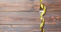 Top view of wrapped fork in tape measure on wooden background. Healthy eating and diet concept Royalty Free Stock Photo