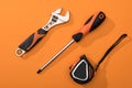 Top view of wrench, screwdriver and measuring tape on orange background Royalty Free Stock Photo