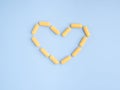 Top view of yellow capsule pills heart shape on a light blue background. Royalty Free Stock Photo
