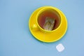 yellow cup of hot tea with tea bag with white mock up label on a blue background Royalty Free Stock Photo