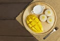 Top view Yellow half mango with small fork. Mango fruit cubes on the wooden table. Tropical fruit asia. Fresh yellow mango peel