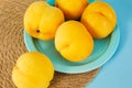 Top view of yellow peaches on a blue plate on a placemat