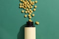 Top view of yellow pills are poured out from the brown bottle with white label for text design on dark green background Royalty Free Stock Photo