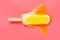 Yellow popsicle in a melting process on pink background