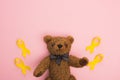 Top view of yellow ribbons with toy on pink background, international childhood cancer day concept.