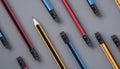 Top view of yellow sharp pencil tip in group of many pencil eraser heads on gray background, concept of conflict, different ideas Royalty Free Stock Photo