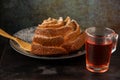 Top view of yogurt sponge cake on dark plate with sugar and wooden fork and glass cup with rooibos tea, selective focus, on wooden