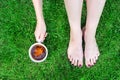 Top view of young adult woman legs and hand holding cup of tea sitting on green grass lawn. Healthcare .Relaxing outdoors concept Royalty Free Stock Photo