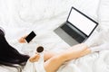 Top view of young asian woman wear white knitwear dress on bed,holding a cup of coffee and mobile phone working with blank screen Royalty Free Stock Photo