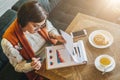 Top view. Young attractive woman, entrepreneur sits in cafe at table and working. Businesswoman is looking at charts Royalty Free Stock Photo