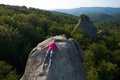 Top view of young attractive woman lying relaxed on top of big mountain rock on bright warm summer day